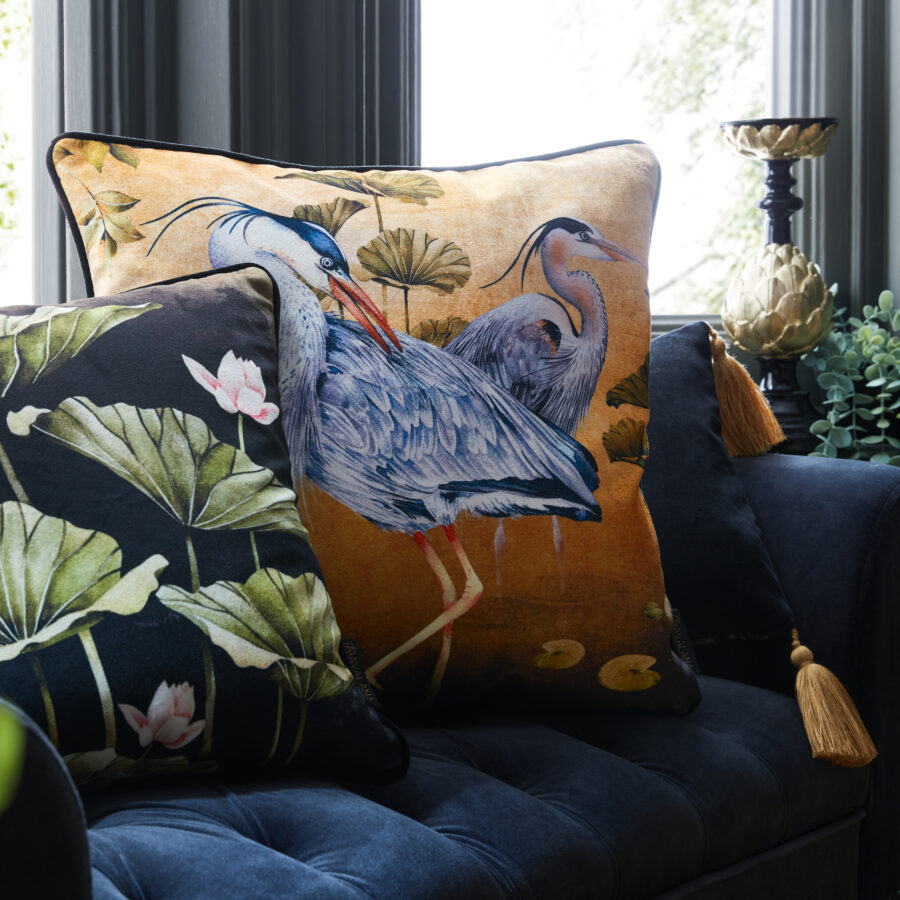Golden orient cushion on a navy ottoman by a window