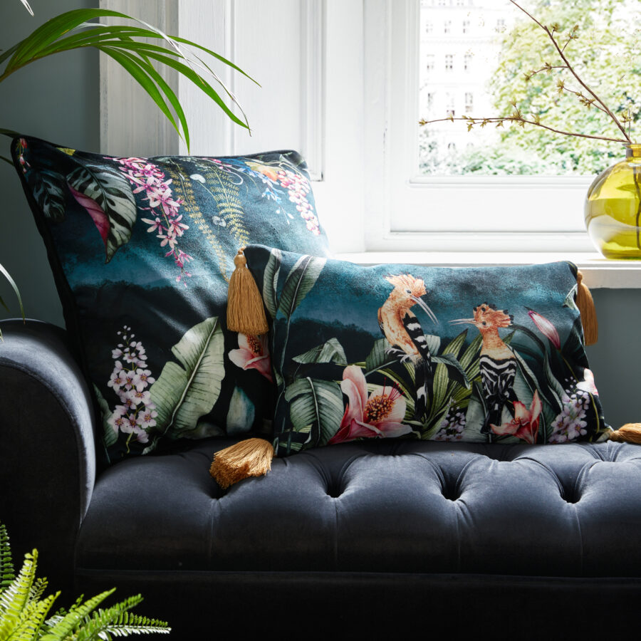 Hoopoe tassel cushion and gardens of Petra floral on a navy ottoman by a window