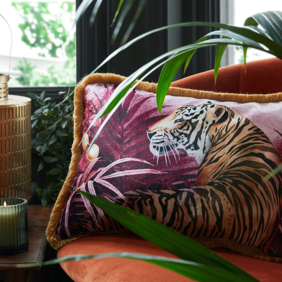 Mulberry tigress cushion with mustard fringe on an orange sitting chair