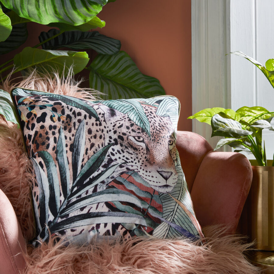 Cantaloupe Jaguar cushion with piping on a blush pink chair by a window