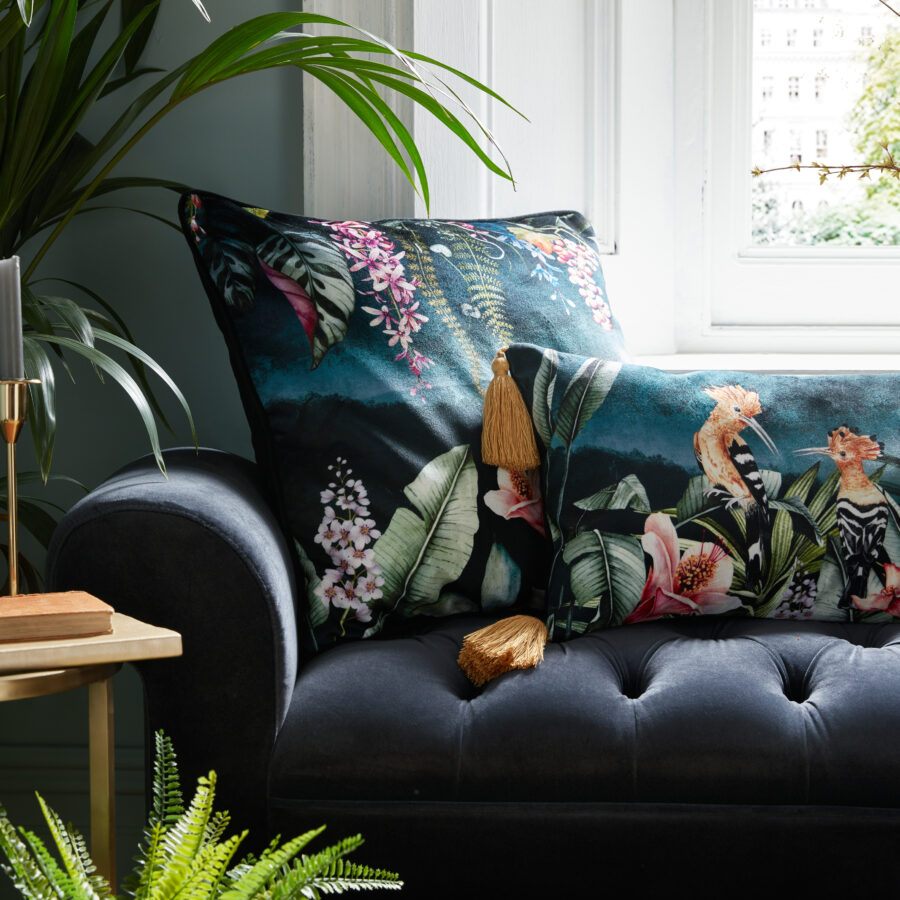 Floral garden and hoopoe cushions on a navy ottoman by a window